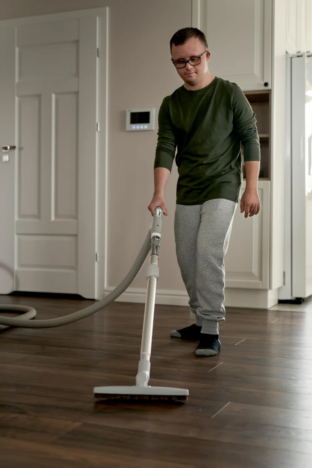 An independent young man vacuuming his apartment