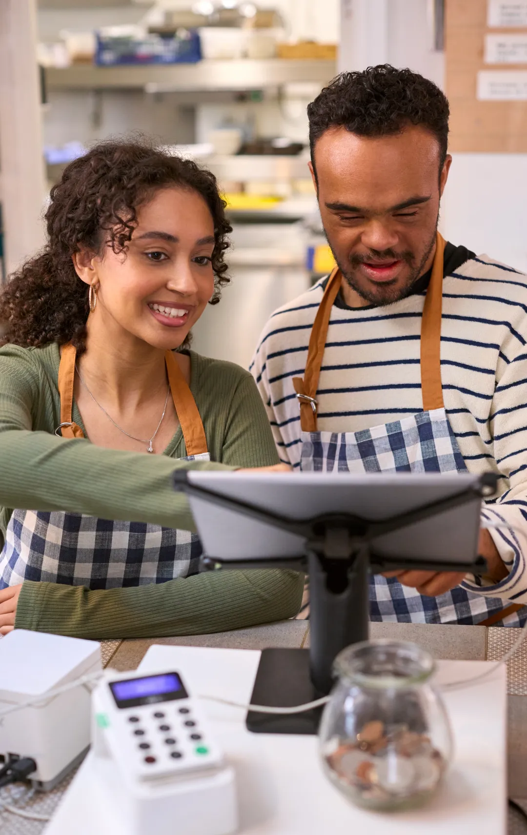 An employee of a coffee shop looking at a tablet with his supervisor