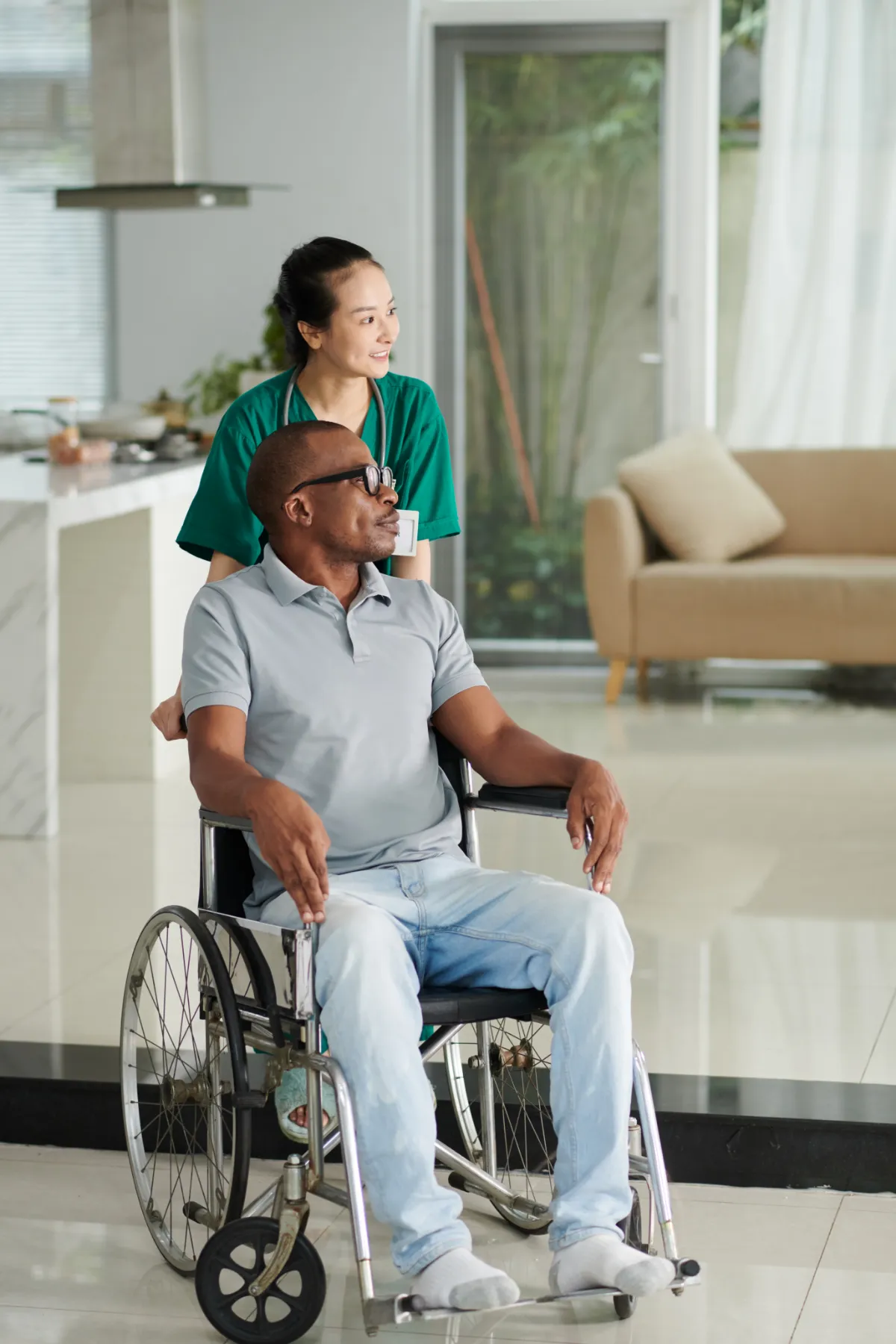 Older Black man being pushed in a wheelchair by a nurse