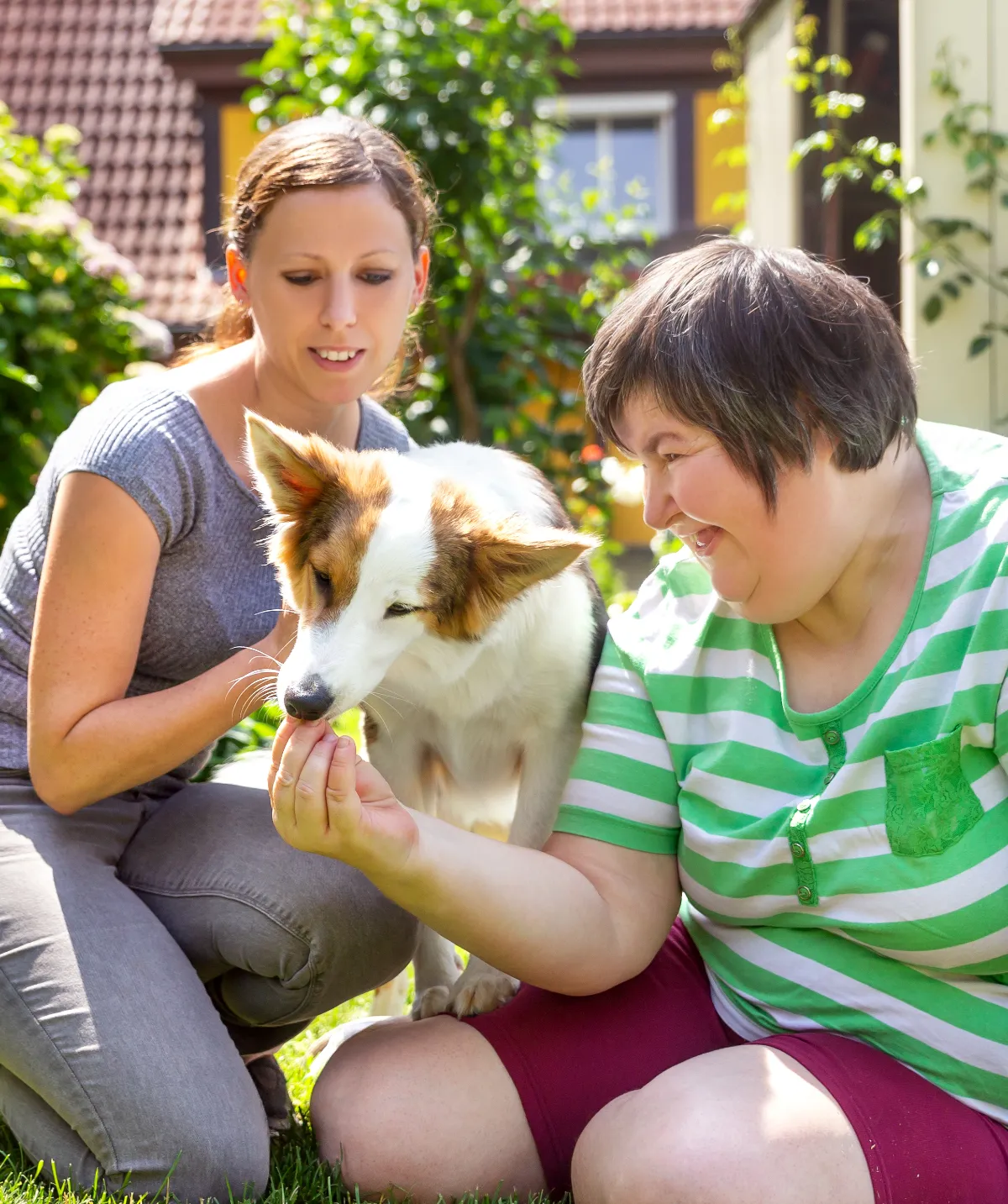 A mentally disabled woman smiling with a dog and another woman